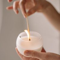 Close-up of a candle being lit by hand, creating a warm, tranquil ambiance.